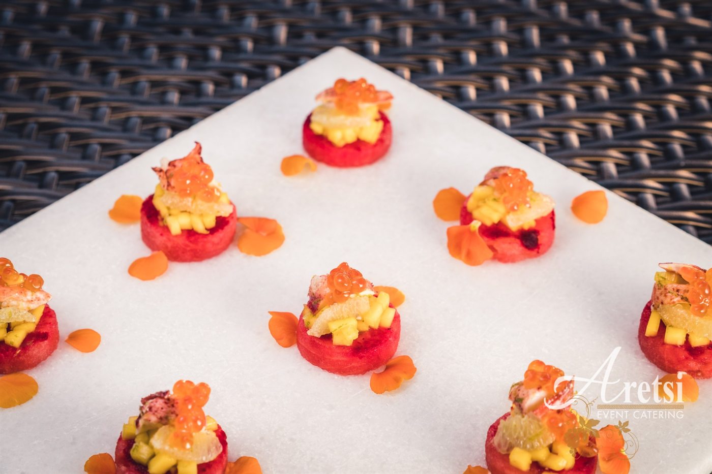 Watermelon canap&eacute;s topped with lobster, mango, citrus and salmon roe on white marble