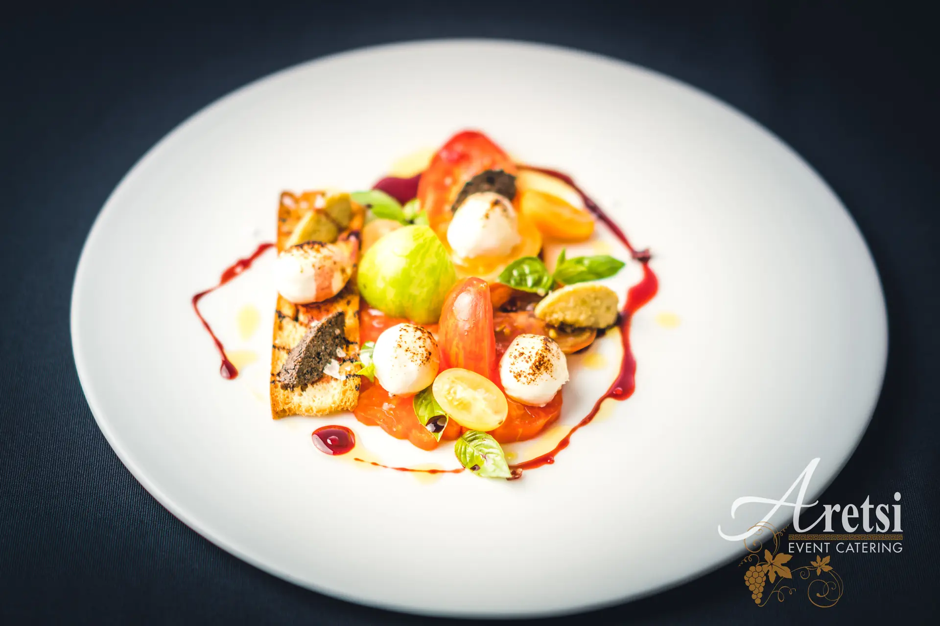 Heritage tomatoes with mozzarella and basil on a white plate, an Aretsi starter