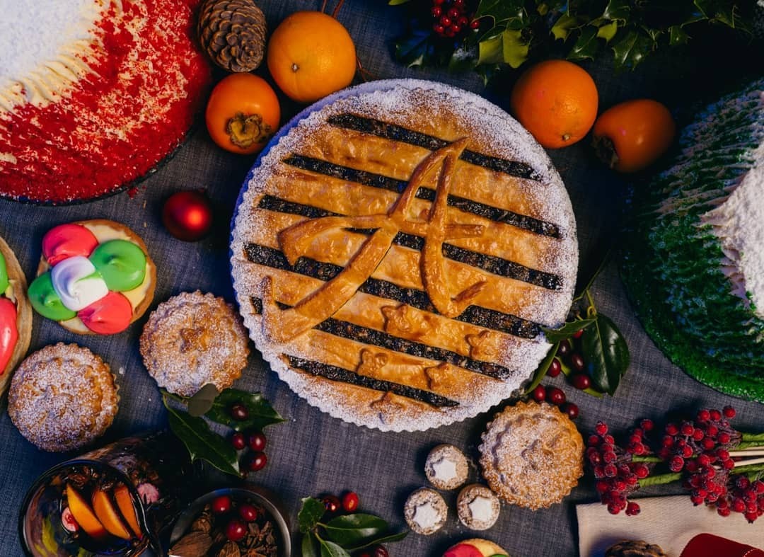 An Aretsi Christmas tart with an A in the pastry lattice, surrounded by mince pies, clementines and holly