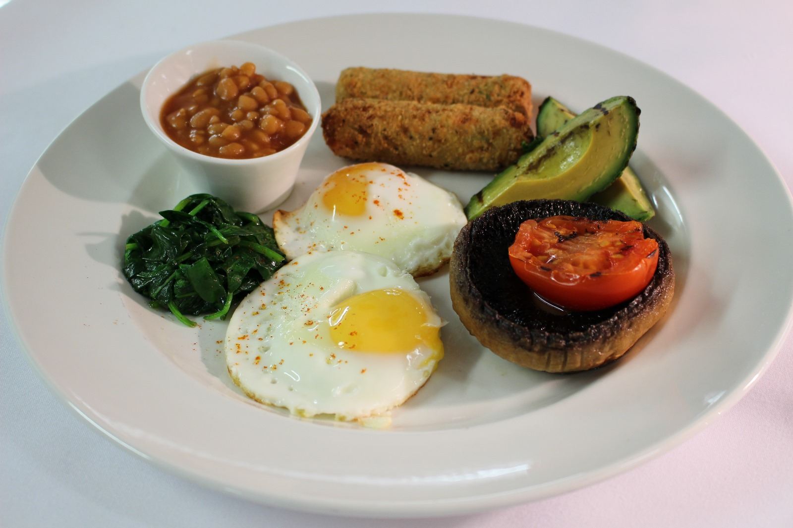 A cooked breakfast with eggs, beans and grilled tomato