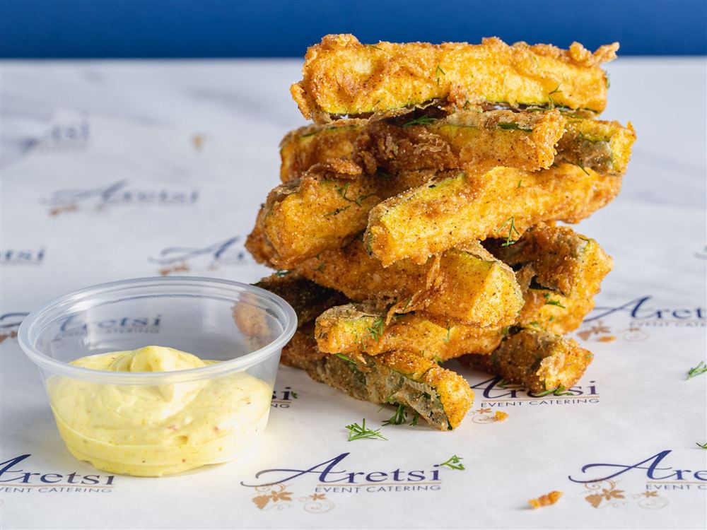 A stack of crispy fried courgette with dill and a pot of dip on Aretsi paper