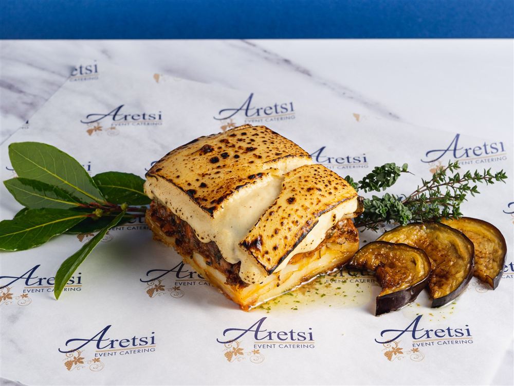 A slice of Aretsi moussaka with a golden béchamel top and roasted aubergine on Aretsi paper