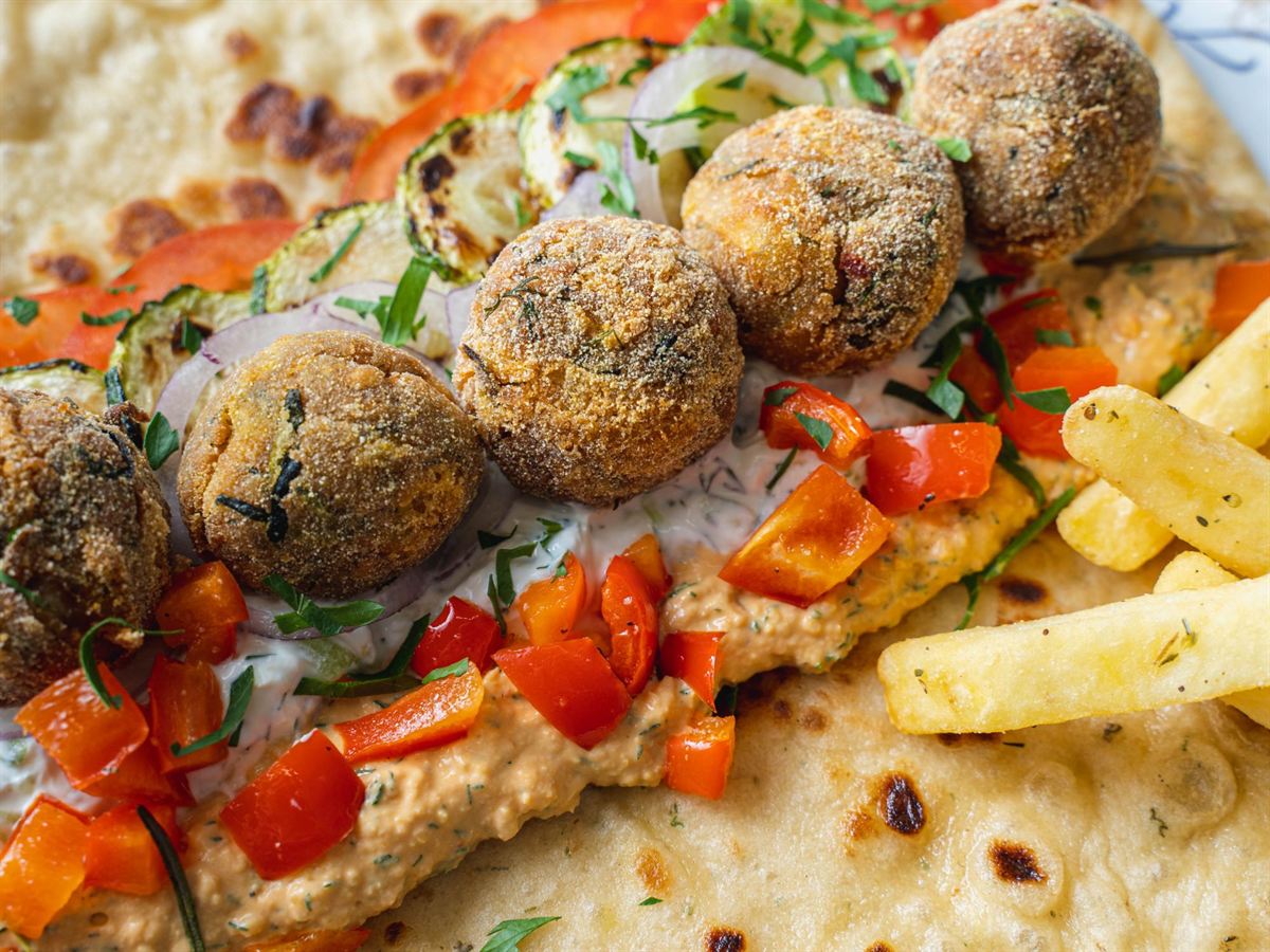 Aretsi falafel on an open pitta with roasted peppers, grilled courgette and dips