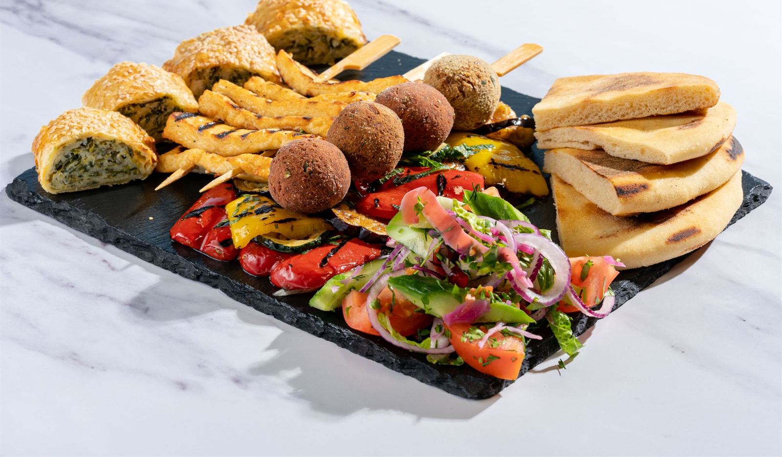 An Aretsi meze platter of spanakopita, halloumi and falafel skewers, chargrilled peppers, Greek salad and warm pittas